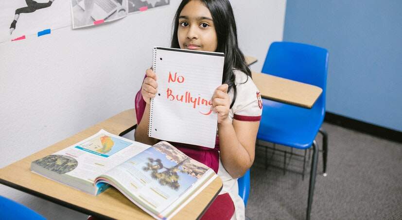 Menina segurando um caderno com a mensagem Stop Bullying
